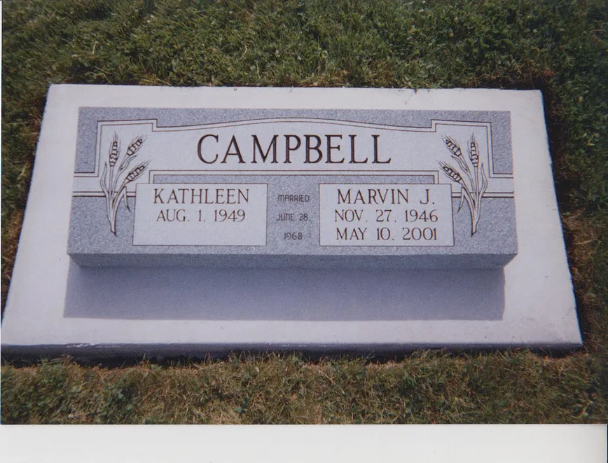 A flat companion marker in light granite set flush in a lawn, engraved with a surname and two names.
