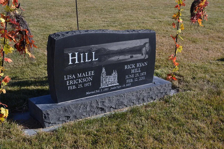 A black granite companion monument with a detailed laser-etched building and landscape scene.